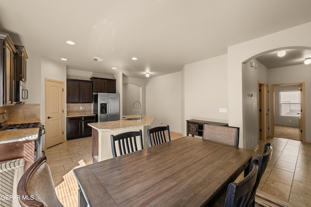 dining space featuring recessed lighting, arched walkways, and light tile patterned flooring