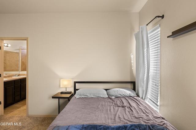 bedroom featuring a sink, ensuite bath, light carpet, and multiple windows