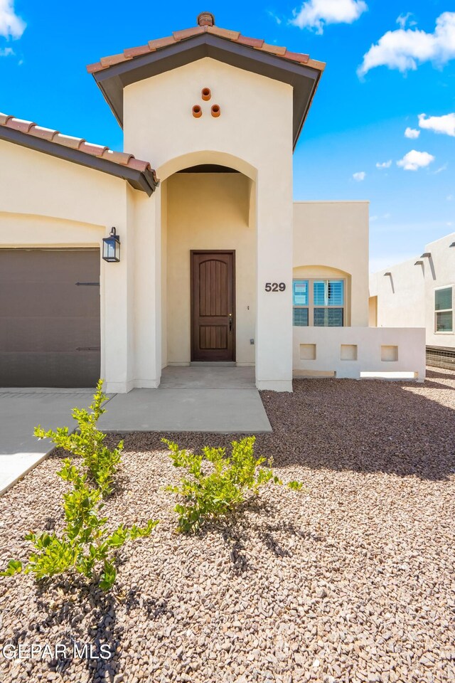 921 Raegil St, El Paso, TX 79928 - property entrance with stucco siding, concrete driveway, and an attached garage