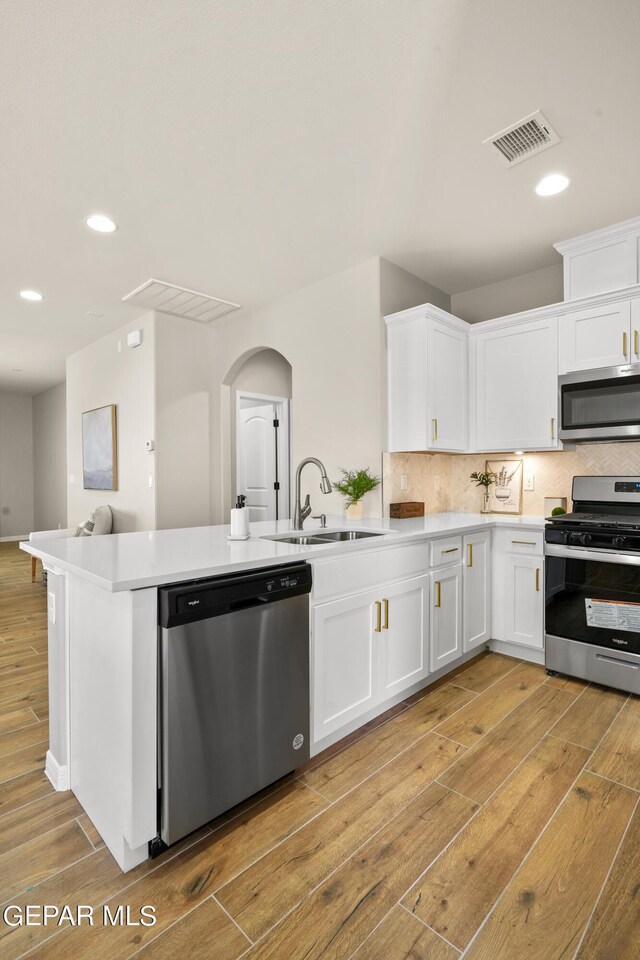 921 Raegil St, El Paso, TX 79928 - kitchen featuring appliances with stainless steel finishes, a sink, light wood-type flooring, a peninsula, and white cabinetry