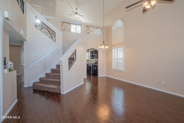 527 Longleaf Pl, El Paso, TX 79928 - unfurnished living room featuring baseboards, ceiling fan with notable chandelier, and a towering ceiling