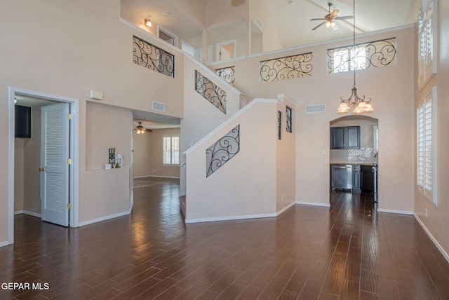 527 Longleaf Pl, El Paso, TX 79928 - unfurnished living room with arched walkways, visible vents, ceiling fan with notable chandelier, and a towering ceiling