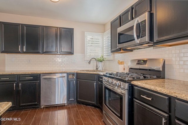 527 Longleaf Pl, El Paso, TX 79928 - kitchen with decorative backsplash, appliances with stainless steel finishes, a sink, light stone counters, and dark wood-style floors