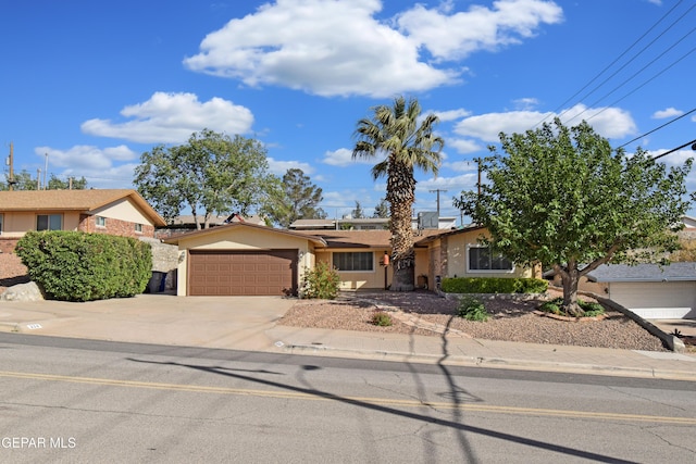 ranch-style home with an attached garage, concrete driveway, stucco siding, and solar panels