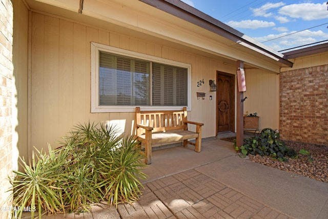 doorway to property featuring brick siding and covered porch