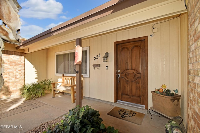 view of exterior entry featuring a porch and brick siding