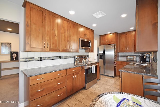 kitchen with backsplash, visible vents, appliances with stainless steel finishes, and a sink