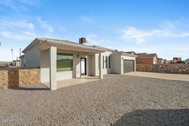 view of front of property featuring an attached garage, central AC unit, stucco siding, and driveway