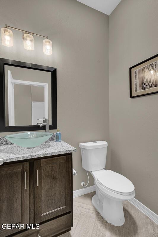 bathroom with baseboards, toilet, and vanity