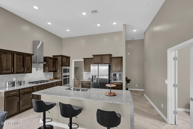 kitchen featuring visible vents, dark brown cabinets, ventilation hood, a sink, and appliances with stainless steel finishes