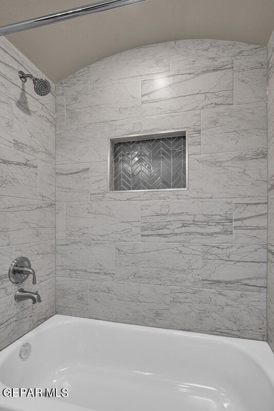 bathroom with bathtub / shower combination and lofted ceiling