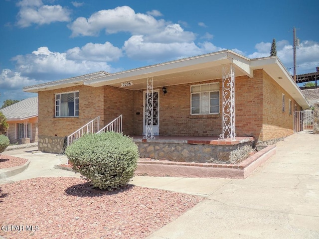 ranch-style house featuring brick siding and covered porch