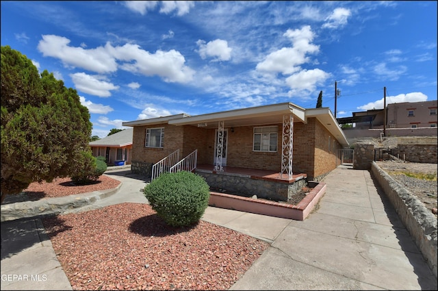 view of front of house with brick siding, a porch, and fence