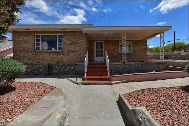 view of front of property with a porch, brick siding, and crawl space