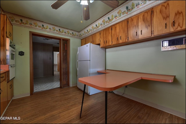 kitchen featuring freestanding refrigerator, wood finished floors, baseboards, brown cabinetry, and ceiling fan