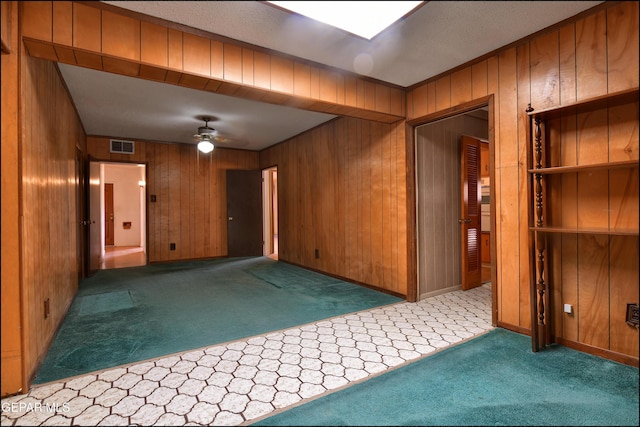 empty room with carpet floors, wooden walls, and ceiling fan