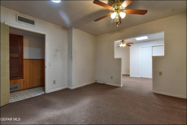 unfurnished room with a ceiling fan, carpet, a skylight, and baseboards