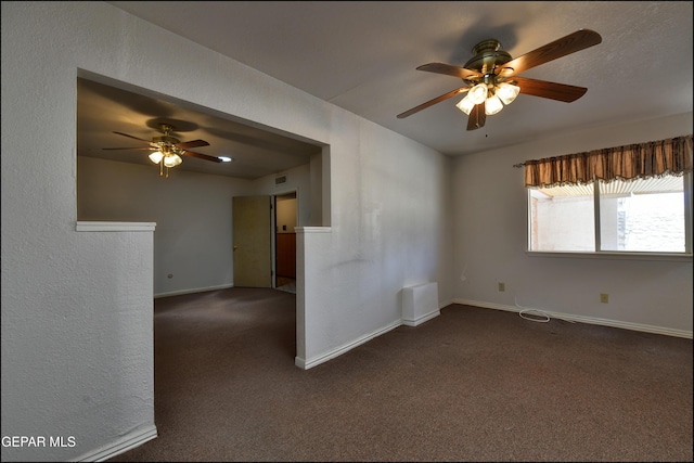 spare room featuring a ceiling fan, dark carpet, and baseboards
