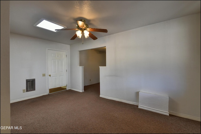 empty room with dark colored carpet, a ceiling fan, and baseboards