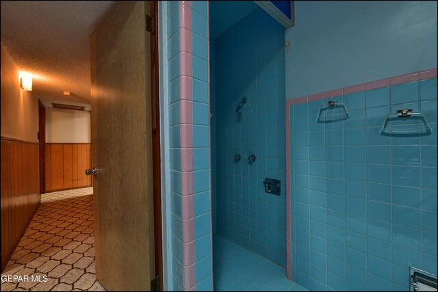 bathroom featuring tiled shower, wainscoting, and tile patterned flooring