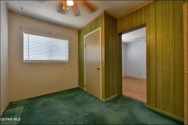 unfurnished bedroom with carpet flooring, a textured ceiling, and wood walls