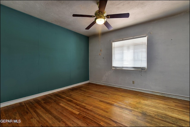 spare room with wood-type flooring, baseboards, a ceiling fan, and a textured ceiling