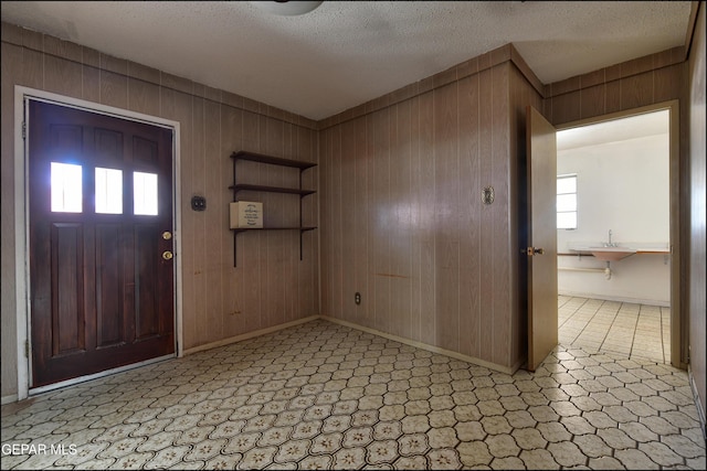 entrance foyer with wood walls, baseboards, and a textured ceiling