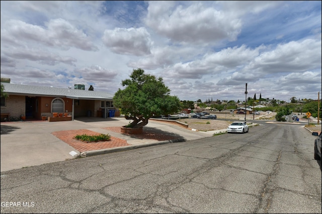 view of asphalt street with curbs and street lights