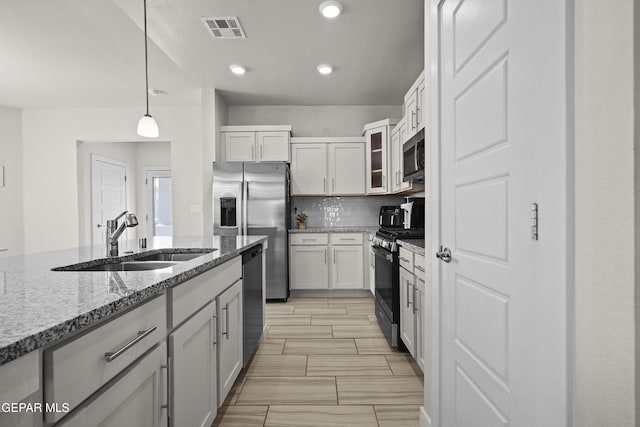 13740 Lago Vista Ave, El Paso, TX 79928 - kitchen featuring stainless steel appliances, a sink, light stone counters, decorative backsplash, and pendant lighting