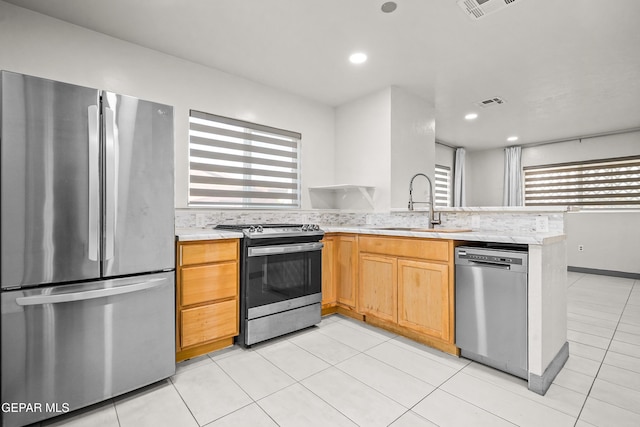 kitchen with a peninsula, light countertops, stainless steel appliances, and a sink