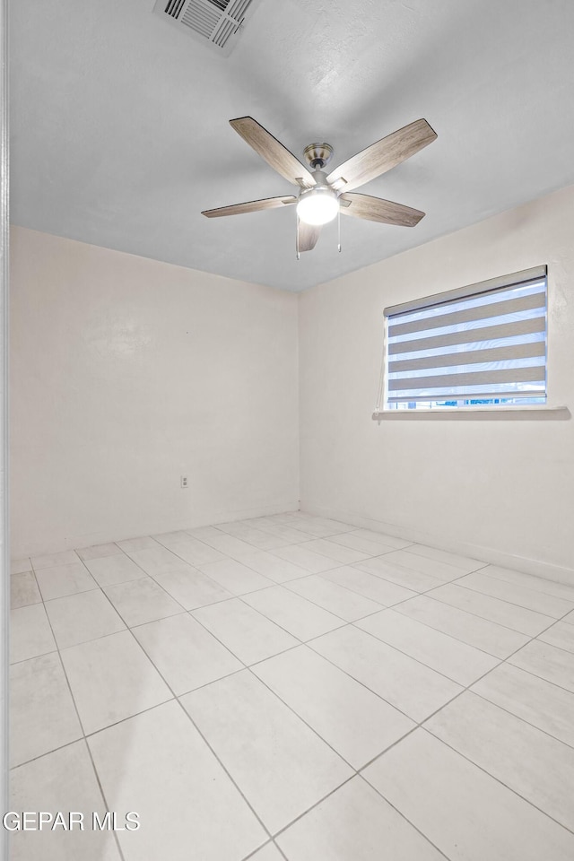 tiled spare room featuring visible vents and ceiling fan