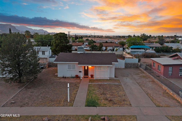 view of front facade featuring fence, concrete driveway, stucco siding, and a mountain view