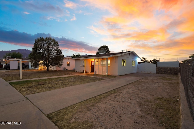 bungalow-style house featuring concrete driveway, stucco siding, and fence