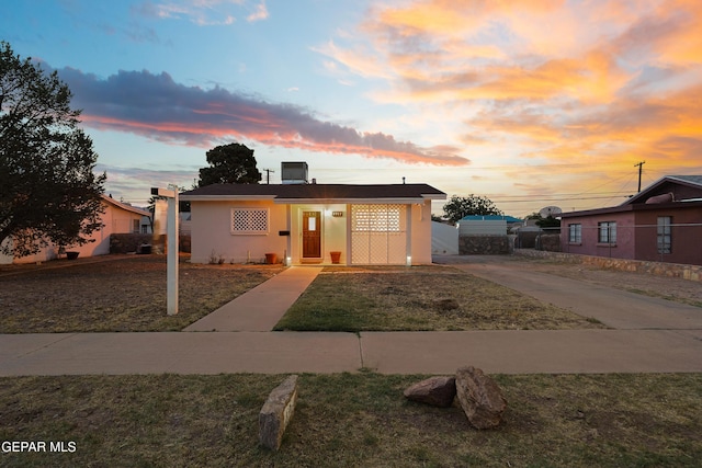 bungalow-style home featuring stucco siding and fence