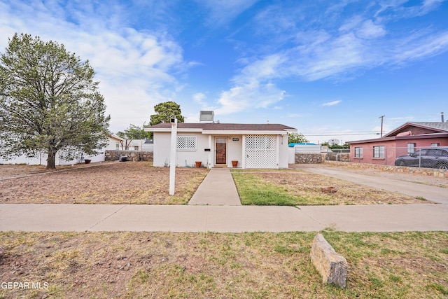 bungalow featuring concrete driveway, stucco siding, and fence