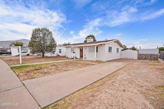 bungalow-style house featuring driveway, stucco siding, a mountain view, and fence