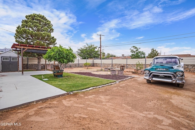 view of yard featuring a patio area, a shed, an outbuilding, a fenced backyard, and a pergola