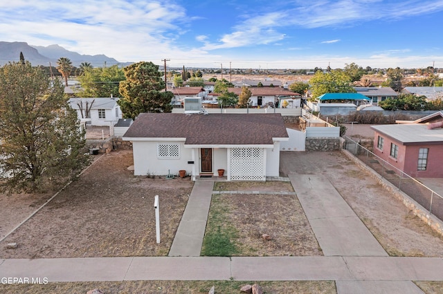 single story home featuring fence, a mountain view, a residential view, stucco siding, and a shingled roof