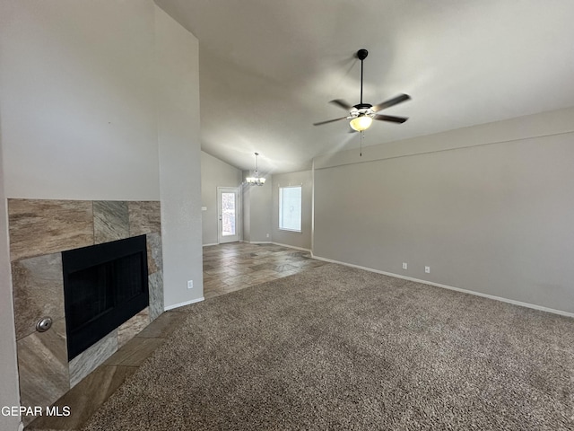 unfurnished living room featuring vaulted ceiling, carpet floors, a ceiling fan, a chandelier, and baseboards