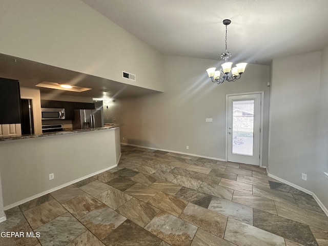 kitchen with stainless steel appliances, stone finish floors, baseboards, a chandelier, and a peninsula