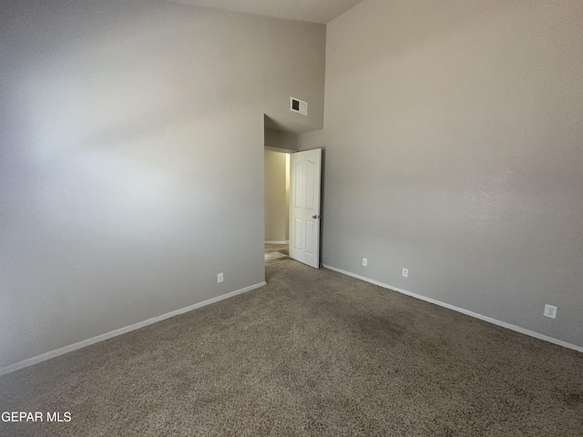 carpeted spare room with baseboards and high vaulted ceiling