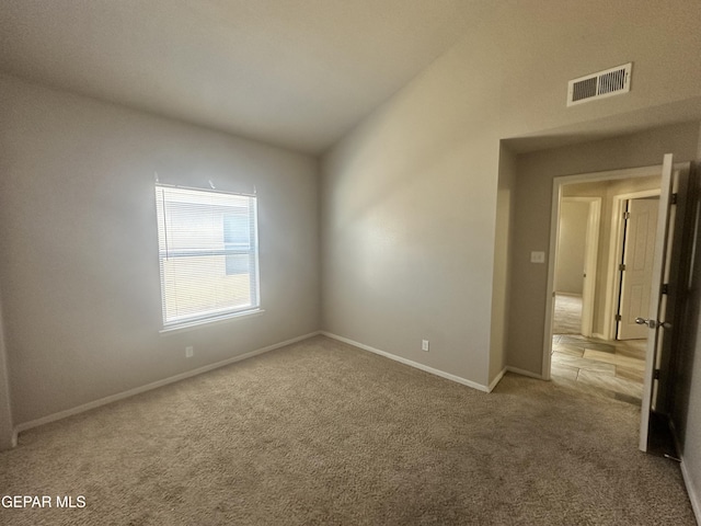 carpeted spare room with baseboards and vaulted ceiling