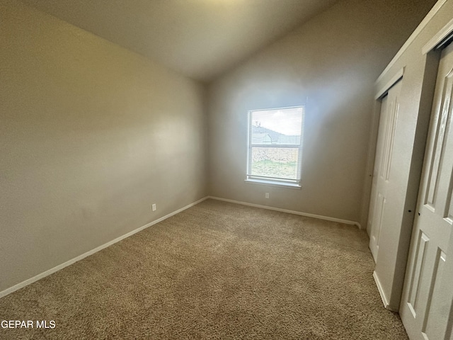 unfurnished bedroom with lofted ceiling, carpet flooring, baseboards, and a closet