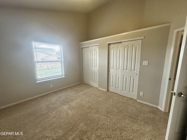 unfurnished bedroom featuring multiple closets, carpet flooring, baseboards, and a high ceiling