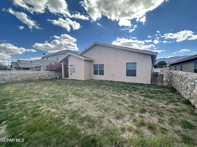 back of house with stucco siding and a gate
