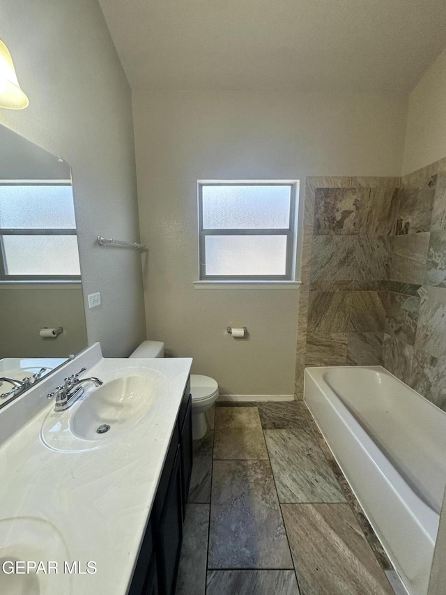 bathroom with plenty of natural light, toilet, a bathtub, and vanity