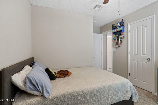 bedroom with ceiling fan, light colored carpet, a textured ceiling, and visible vents