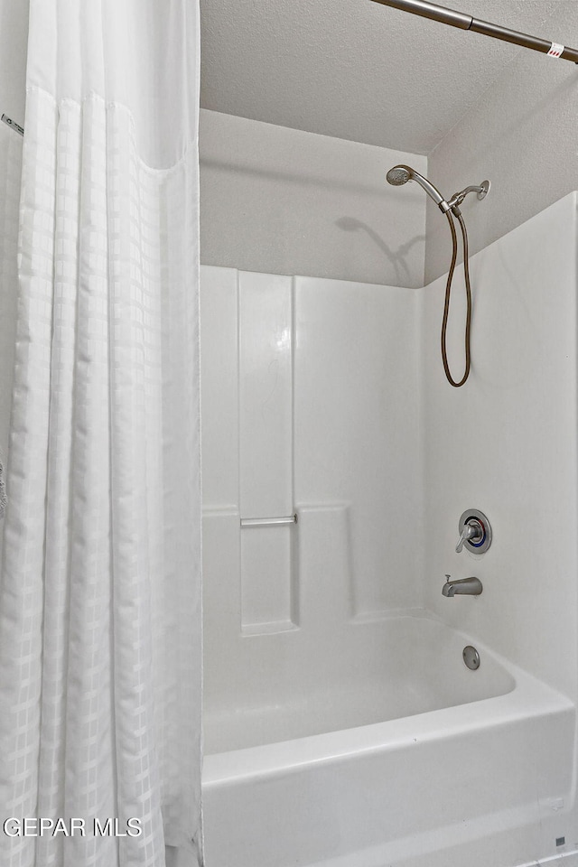 full bathroom with a textured ceiling and shower / bath combination with curtain