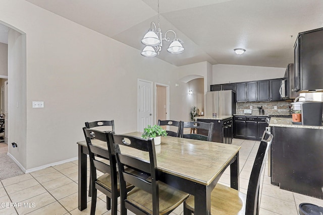 dining area featuring lofted ceiling, light tile patterned flooring, baseboards, arched walkways, and a notable chandelier