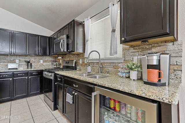 kitchen featuring decorative backsplash, vaulted ceiling, a sink, stainless steel appliances, and light tile patterned flooring